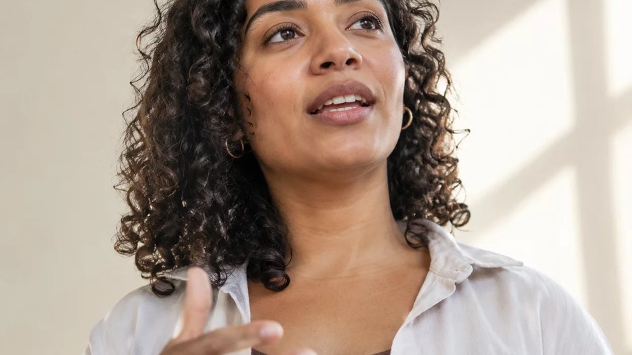 Duas participantes sentadas frente a frente numa mesa da sala do Rio de Janeiro; a da direita rascunha a resposta que vai dar
